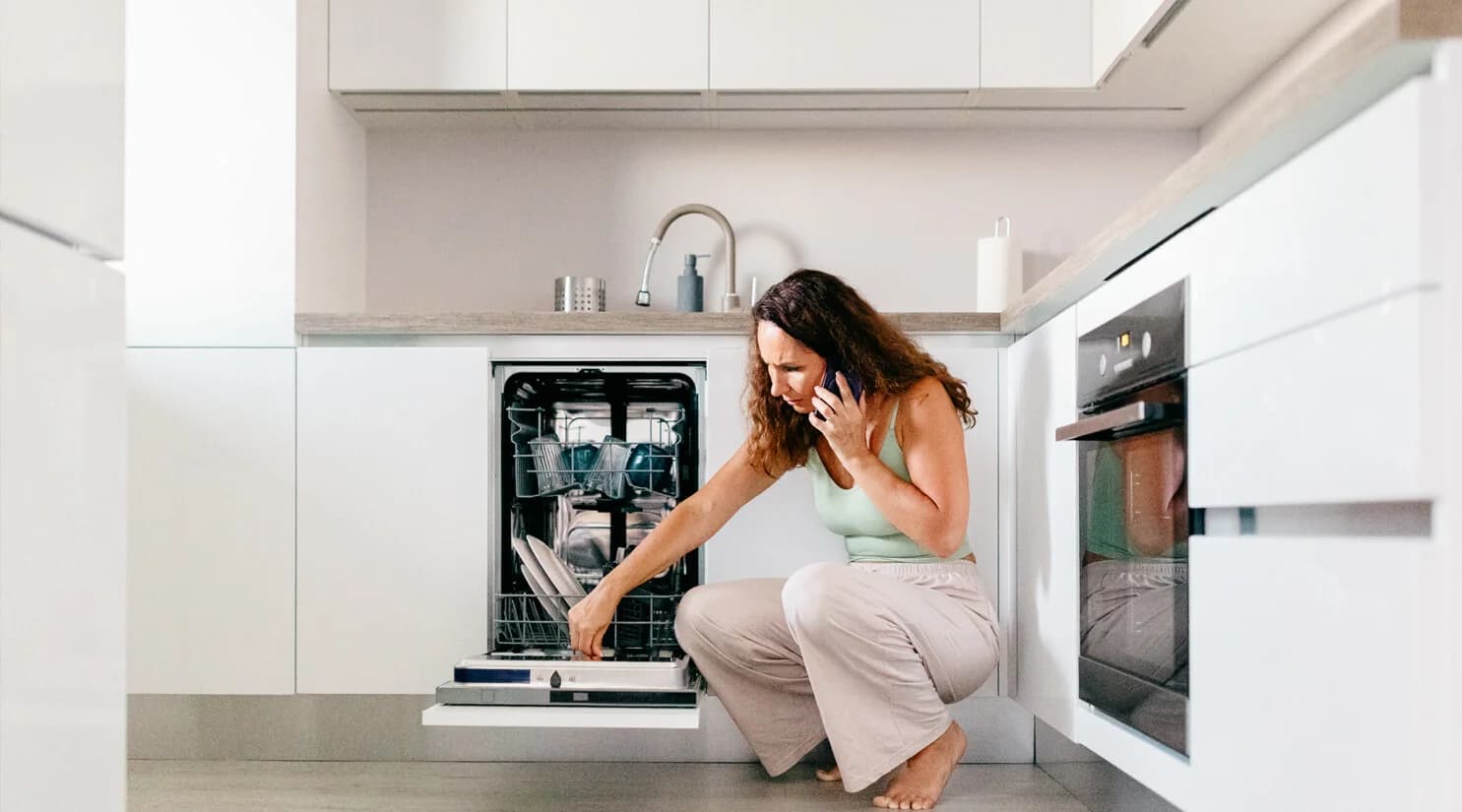 Homeowner checking a dishwasher while speaking on the phone